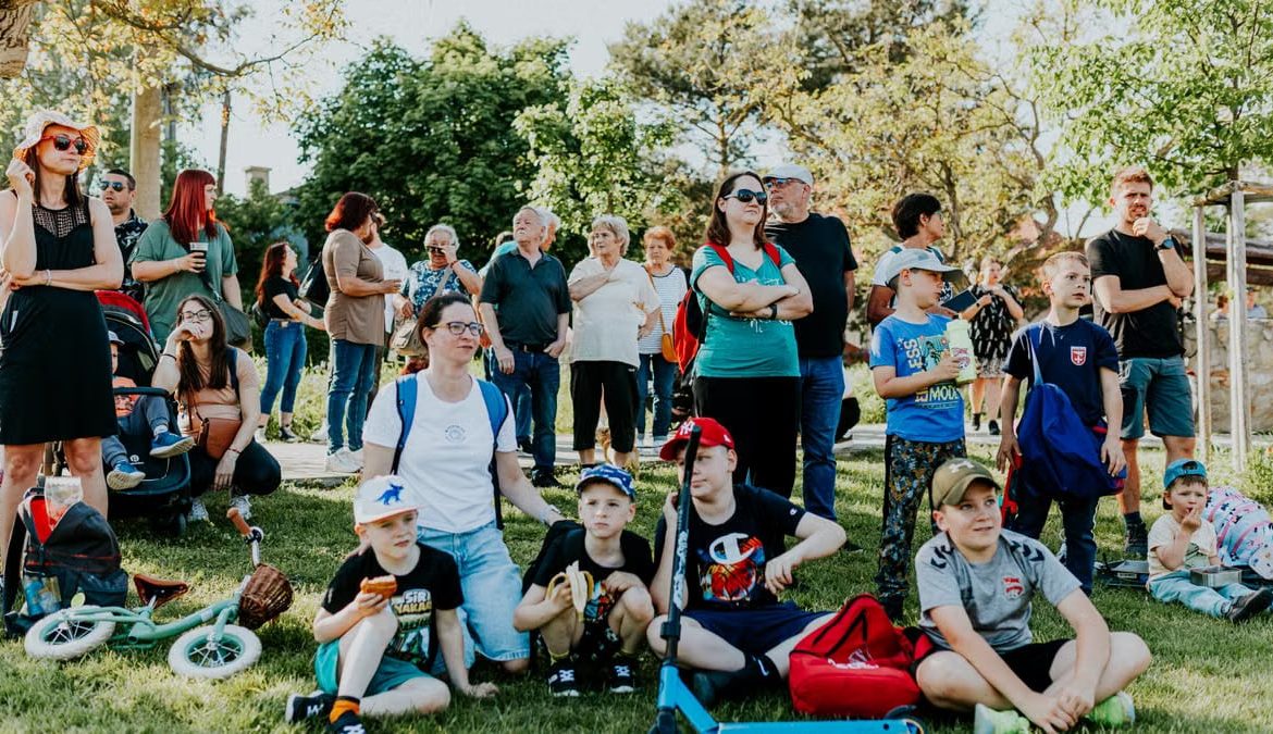A diverse group of people enjoying a sunny day at an outdoor community event in a park setting.