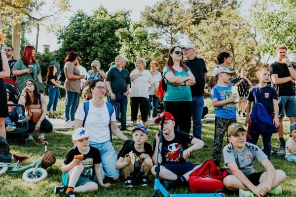 A diverse group of people enjoying a sunny day at an outdoor community event in a park setting.