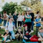 A diverse group of people enjoying a sunny day at an outdoor community event in a park setting.